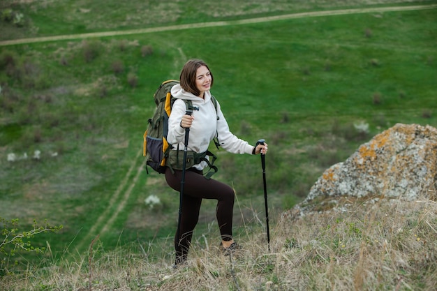 Ein schönes europäisches Mädchen wandert in den Bergen. Eine weiße Frau reist mit Rucksack in der Natur.