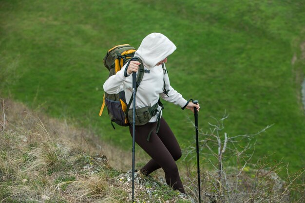 Ein schönes europäisches Mädchen wandert in den Bergen. Eine weiße Frau reist mit Rucksack in der Natur.