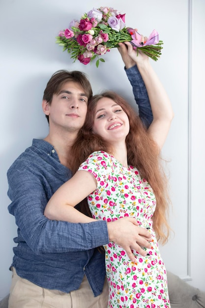 Ein schönes Familienpaar, ein Mann und eine Frau mit einem Blumenstrauß, lächeln fröhlich und schauen in die Kamera