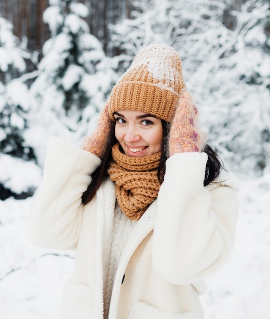 Ein schönes fröhliches lachendes junges Mädchen in Handschuhen und einem Winterhutschal, bedeckt mit Schneeflocken.