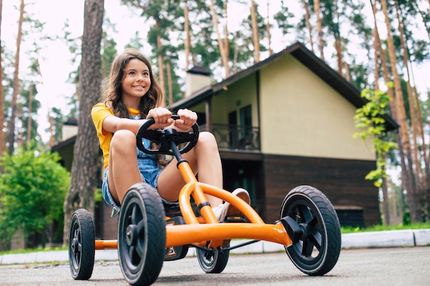 Ein schönes glückliches kleines Mädchen im Urlaub fährt Fahrrad und hat Spaß im Sommerwaldcamp