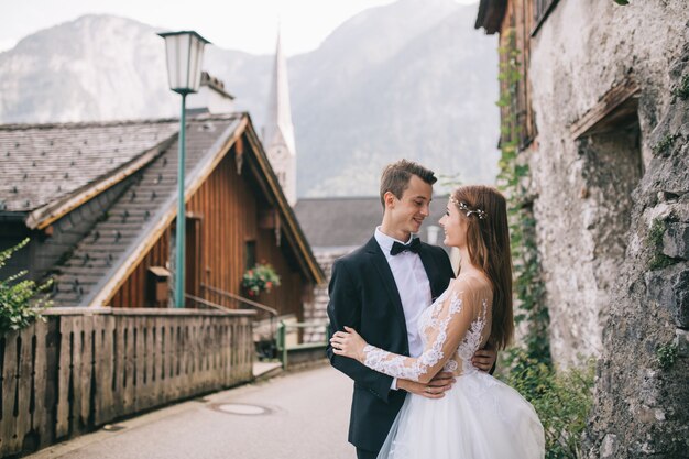 Ein schönes Hochzeitspaar geht in eine feenhafte österreichische Stadt, Hallstatt.