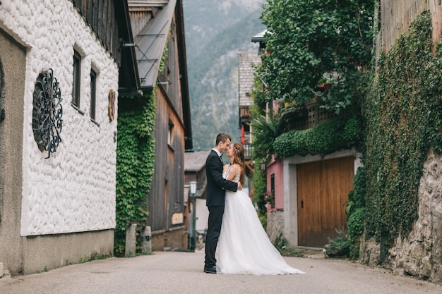 Ein schönes Hochzeitspaar geht in eine feenhafte österreichische Stadt, Hallstatt.