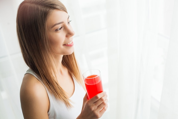 Ein schönes junges mädchen, das der zahl folgt und saft trinkt, das konzept der gesunden ernährung, weiß