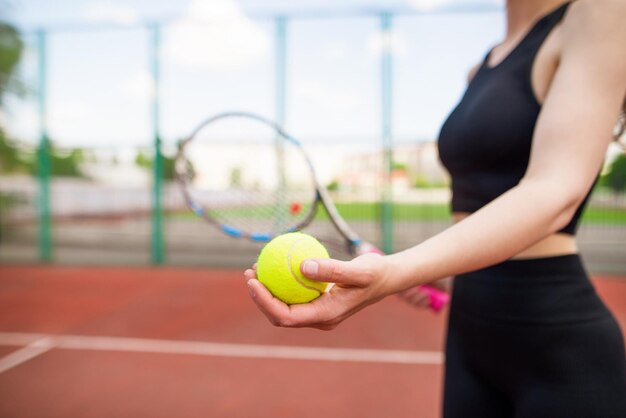 Ein schönes junges Mädchen, das einen Tennisball und ein Schläger in der Hand hält, bereitet sich darauf vor, einen Tennisball zu servieren.