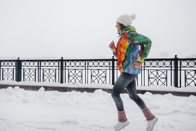 Ein schönes junges Mädchen joggt an einem frostigen und schneereichen Tag. Sport, gesunder Lebensstil