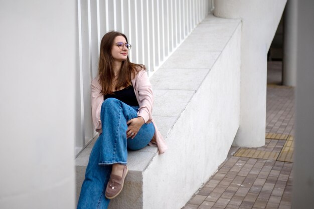 Foto ein schönes junges mädchen mit brille und beigem hemd sitzt allein und blickt in die ferne