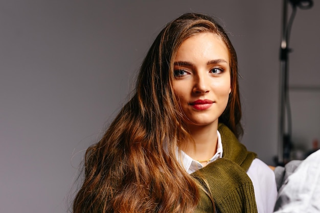 Ein schönes junges Mädchen mit langen Haaren und blauen Augen lächelt auf einem Studiohintergrund mit Kopierraum