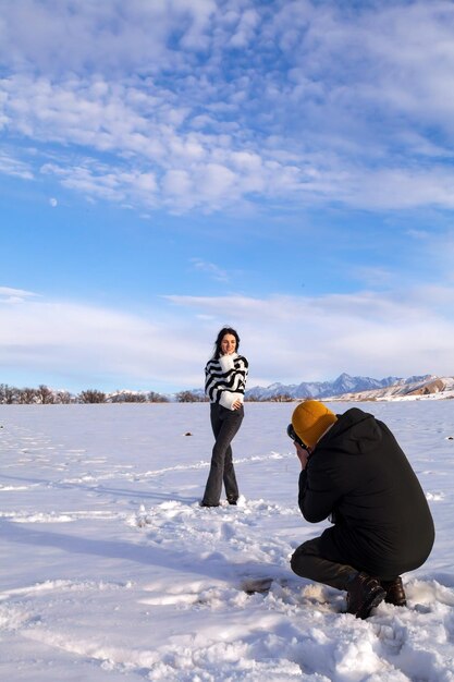 Ein schönes junges Paar Touristen, ein Mann und eine Frau, fotografieren als Souvenir in der Winterlandschaft