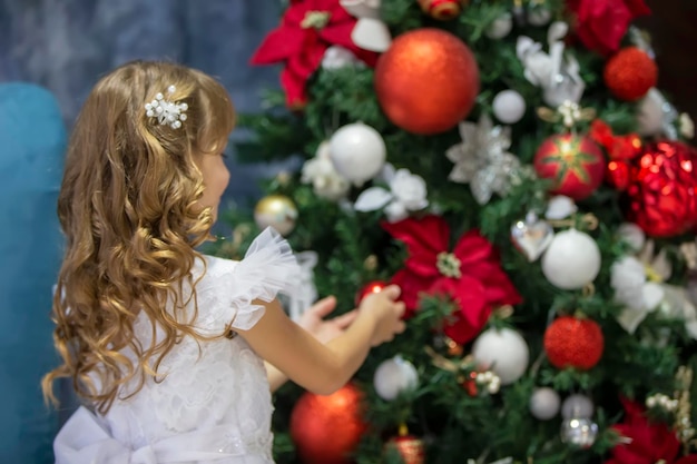 Ein schönes Kind schmückt einen Weihnachtsbaum Elegantes Mädchen in der Weihnachtszeit