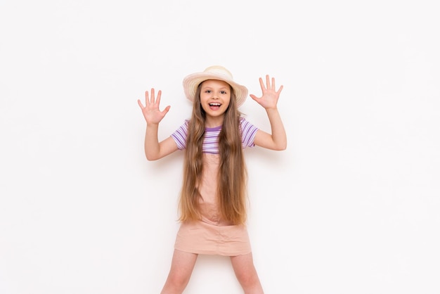 Ein schönes kleines Mädchen in einem Sommerkleid und einem Strohhut bereitet sich auf einen Sommerurlaub vor Sommerferien für Kinder White isolated Background