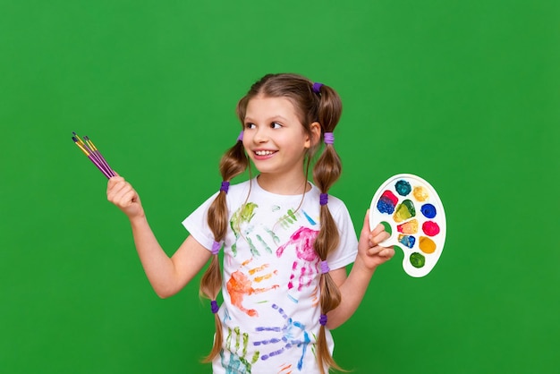 Ein schönes kleines Mädchen mit Farben und Pinseln lächelt Zeichenkurse für Kinder und die Entwicklung der Kreativität von Kindern