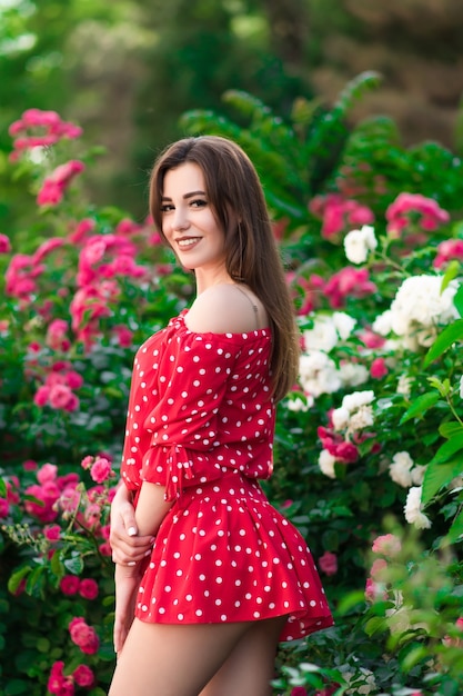 Ein schönes Mädchen in einem roten Kleid geht im Park spazieren und posiert in einem Kleid Modekonzept