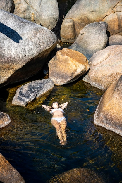 Ein schönes Mädchen in einem weißen Bikini liegt auf dem Wasser in einem natürlichen Pool in Jourama Falls, Australien