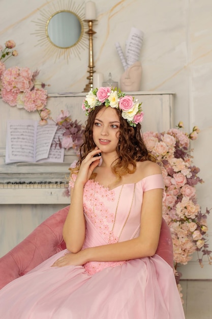 Foto ein schönes mädchen mit einem blumenkranz auf dem kopf und in einem langen rosa kleid wird in einem fotostudio frühling photosession fotografiert