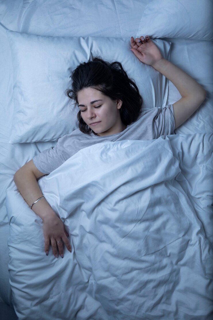 Ein schönes Mädchen schläft in einem Bett mit einem weißen Laken