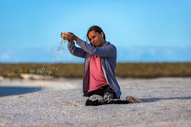 Ein schönes Mädchen spielt bei Sonnenuntergang mit Muscheln am berühmten Muschelstrand in Westaustralien