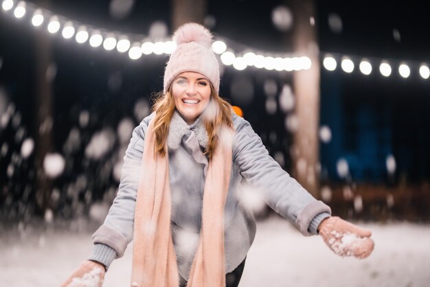 Ein schönes Mädchen spielt mit Schnee Fröhliche Winterzeit im Wald Festliche Girlandenlichter