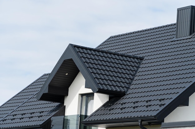 Foto ein schönes modernes haus ist mit schwarzen metallfliesen bedeckt. überdachung aus metallprofil in wellenform