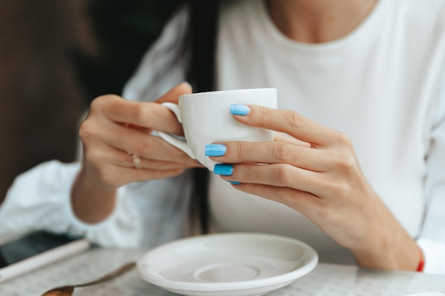 Ein schönes süßes Mädchen in einem Café trinkt Kaffee an einem Tisch.