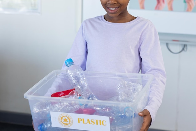 Ein Schüler mit einem Plastikbehälter lächelt im Klassenzimmer in der Schule