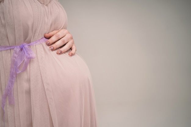 Ein schwangeres Mädchen hält ihren Bauch. Eine junge Mutter erwartet die Geburt eines Kindes. Frau umarmt sanft ihr Baby im Bauch.