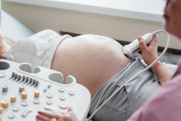 Ein schwangeres Mädchen hat in der Klinik in Nahaufnahme einen Ultraschall des Abdomens. Medizinische Untersuchung