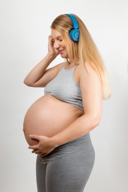 Ein schwangeres Mädchen hört Musik mit Kopfhörern Der Einfluss von Musik auf das Baby