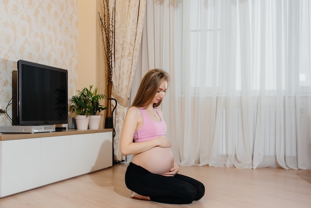 Ein schwangeres Mädchen macht zu Hause Yoga. Gesundheit