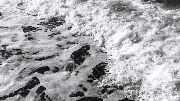 Ein Schwarz-Weiß-Foto eines Meeres mit Fußspuren im Wasser.