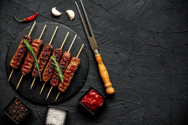 Ein schwarzer Hintergrund mit einem Teller mit Kebabs und Chilischoten.