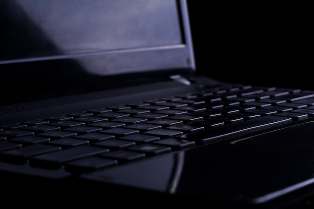 Ein schwarzer Laptop auf schwarzem Hintergrund isoliert