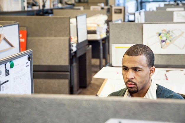 Ein schwarzer Mann, der in seiner Kabine in einem Firmenbüro arbeitet