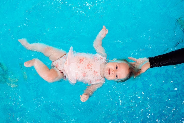 Ein Schwimmlehrer bringt einem Kind das Schwimmen im Pool bei.