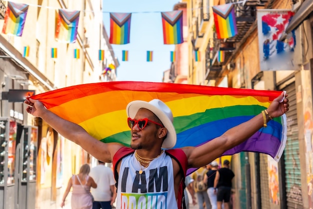 Ein schwuler schwarzer Mann, der auf der Pride-Party mit einer LGBT-Flagge eine Sonnenbrille trägt