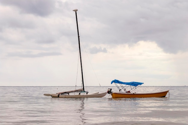 Foto ein seesegelboot und ein fischerboot sind in einem ruhigen hafen seascape festgemacht