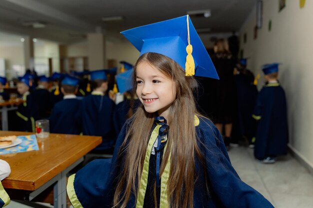 ein sehr fröhliches und glückliches kleines Mädchen in einer Uniform der ersten Klasse lächelt während einer Schulfeier süß für die Kamera