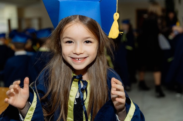 ein sehr fröhliches und glückliches kleines Mädchen in einer Uniform der ersten Klasse lächelt während einer Schulfeier süß für die Kamera