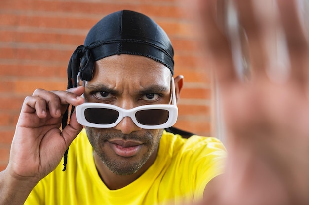 Ein selbstbewusster urbaner Tänzer repariert seine Sonnenbrille