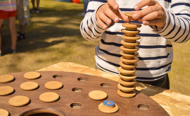 Ein selektiver Fokus eines Jungen, der aus den Details eines Holzspiels einen Turm zusammenbaut