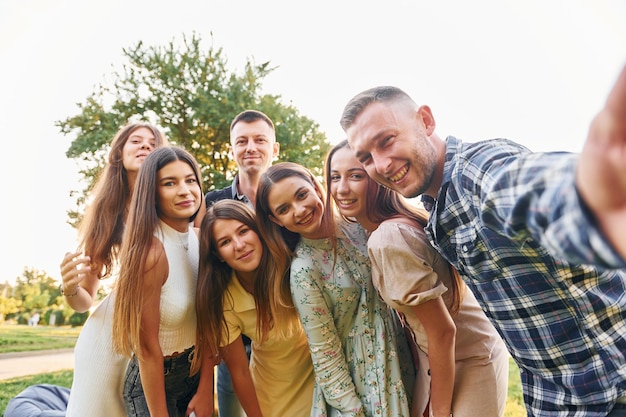 Ein Selfie machen Eine Gruppe junger Leute feiert tagsüber im Sommer eine Party im Park