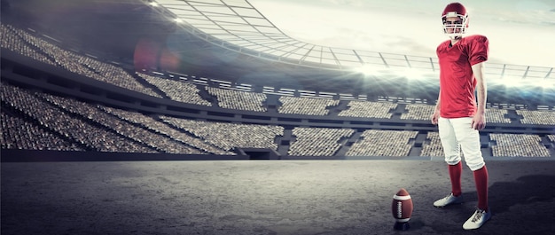 Foto ein seriöser american-football-spieler, der seinen helm nimmt und die kamera gegen das rugby-stadion betrachtet