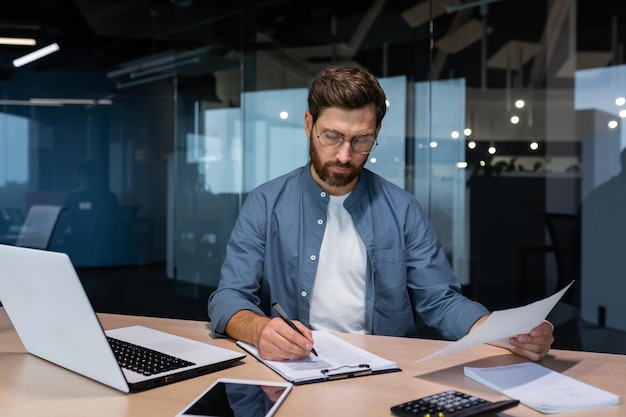 Ein seriöser junger Mann, Buchhalter, Finanzanalyst, Wirtschaftsprüfer, sitzt im Büro am Tisch, mit dem er arbeitet