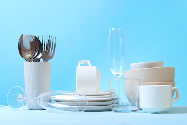 Ein Set Geschirr und Küchenutensilien auf farbigem Hintergrund