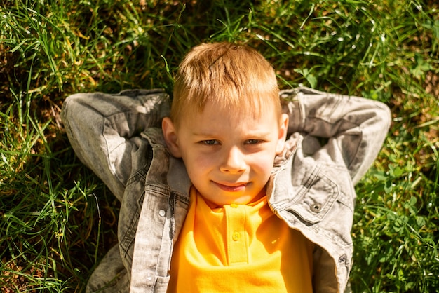 Ein siebenjähriger Junge liegt im Sommer auf dem Rasen