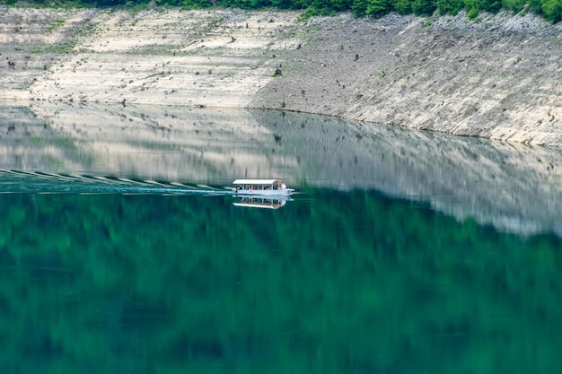 Ein Sightseeing-Boot mit Touristen schwimmt entlang des malerischen Sees zwischen den Canyons
