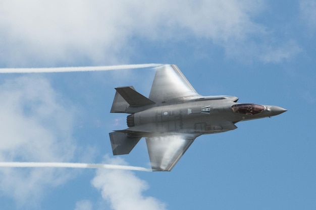 Ein silberner F-35-Jet fliegt durch den Himmel mit der Aufschrift „F-35“ auf dem Heck.