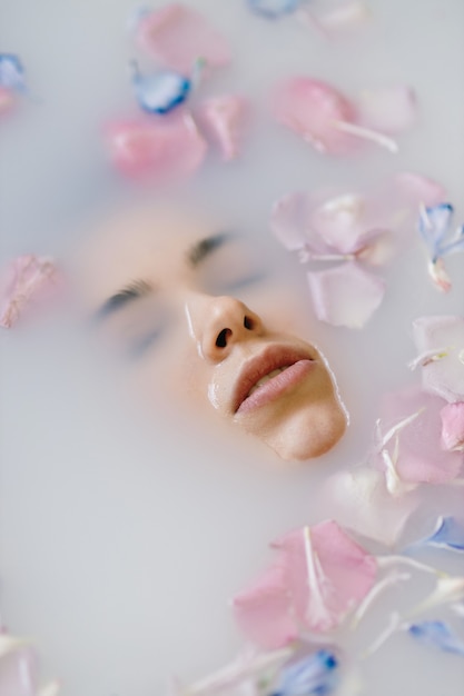 Ein sinnliches Porträt einer Frau in einem Bad mit Milch und Blumen Spa-Behandlungen weiche Haut