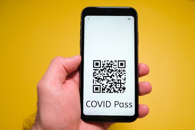 Ein Smartphone mit elektronischem Immun-Digital-Gesundheitspass Covid-Pass mit QR-Code in der Hand des Mannes