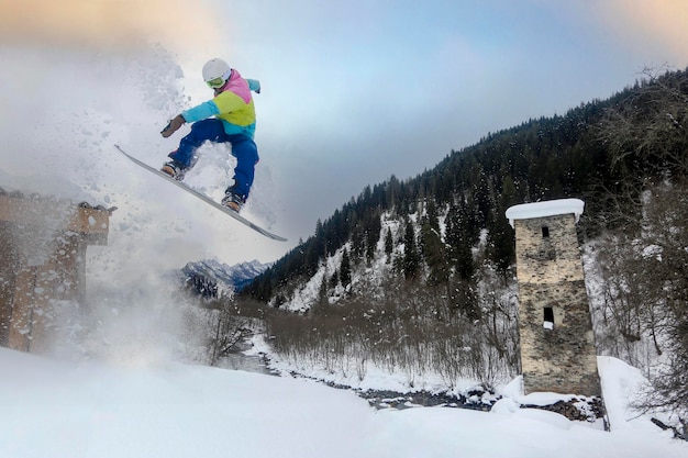 Ein Snowboarder springt über den historischen Svan Tower im Mestia Georgia Love Tower